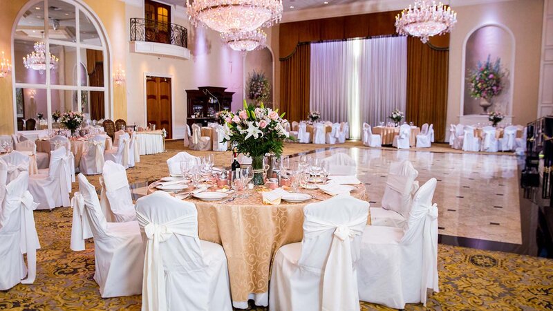 Ballroom. Nine tables. Gold table cloth. White seat covers.