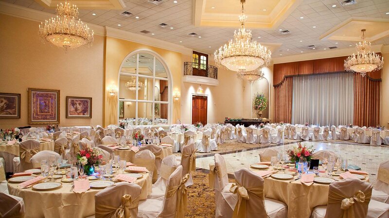 Thirteen tables in ballroom. Gold table cloth, gold napkins and gold seat cover accents.